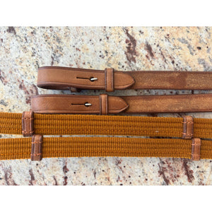 Gurtzügel flach Cognac mit Leder Martingalschiebern in edlem Cognacton auf Steinuntergrund. Robuste Zügel für Reiterzubehör und Pferdesport.
