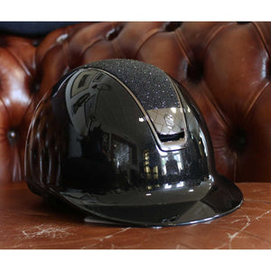 Samshield Reithelm Glossy Top Crystal Fabrics mit Chrome Blason & Trim auf braunem Ledersessel. Hochwertiger Reithelm für Sicherheit & Komfort.