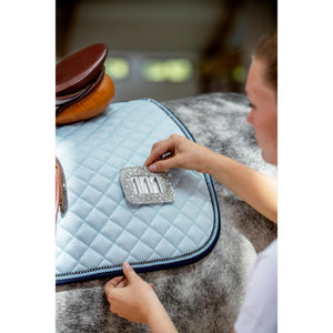 Reiterin befestigt HorseGuard Startnummern mit Glitzer an Sattelunterlage. Einfach wechselbare Turniernummer für Pferde im Einsatz.