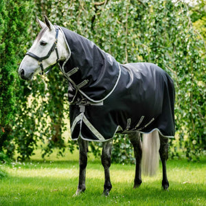 Horseware Amigo Bravo 12 wasserdichte Weidedecke mit 250g Füllung und Halsteil auf grauem Pferd im Garten. Ideal für Winter 2024.