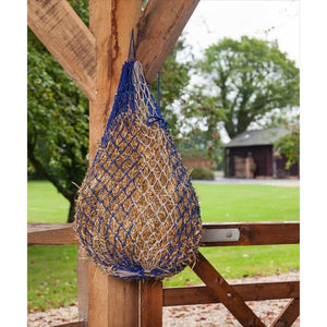 Le Mieux Heunetz Hippo Haynet black/grey mit kleinen Öffnungen für langsames Fressen, aufgehängt an einem Holzpfosten im Stallbereich. Ideal zur Förderung der Verdauung und Reduzierung von Futterverschwendung bei Pferden.