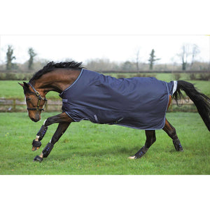 Amigo Bravo 12 Pferdedecke 400g in Dunkelblau auf galoppierendem Pferd auf grüner Weide. Wasserdichte und atmungsaktive Weidedecke für kalte Tage.