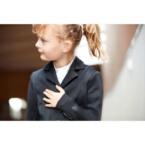 Mädchen trägt das Equipage Turnierjacket Kinder in Schwarz. Elegantes Reitjacket mit Glitzersteinen am Kragen für stilvolle Auftritte.