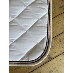 Nahaufnahme der Quola Springschabracke mit roséfarbener Kordel und beigem Rand. Elegante Schabracke für Reitsport und Pferdezubehör.