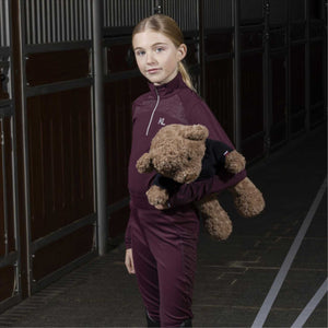 Mädchen in Reitkleidung hält Kingsland Teddybär KLVinnie, ideales Accessoire und Geschenk aus der Winterkollektion für junge Reiter.