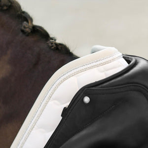 Detailansicht der weißen Equestrian Schabracke mit Glitter-Rand unter schwarzem Sattel. Hochwertige Sattelunterlage mit edlem Finish.