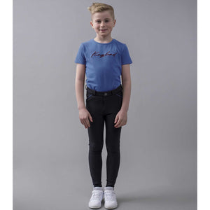 Kind trägt das blaue Kingsland Kinder T-Shirt Unisex mit rotem Stickzug, kombiniert mit Reithose – bequeme Kinderoberbekleidung für aktive Tage.
