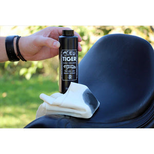 Anwendung der Bense&Eicke Tiger Lederschwärze 250 ml auf schwarzem Sattel mit Tuch. Perfekt zur Pflege und Farbauffrischung von Lederflächen.